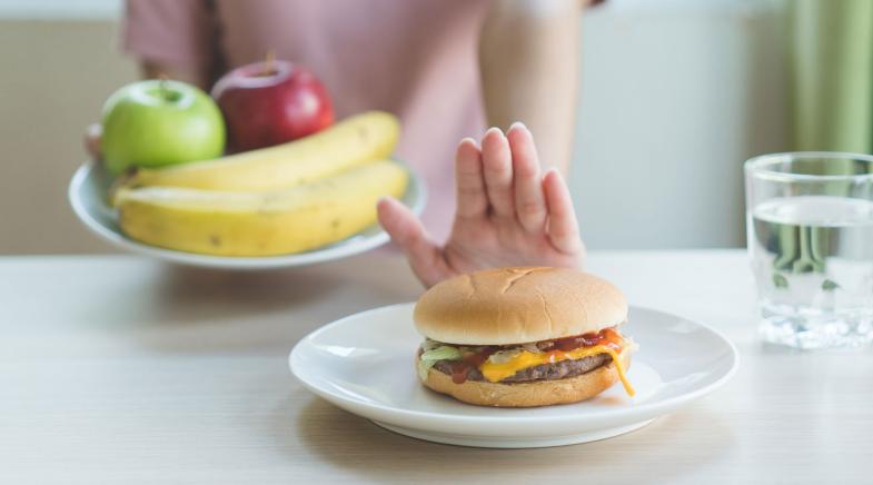 Person entscheidet sich für Obst anstatt Burger