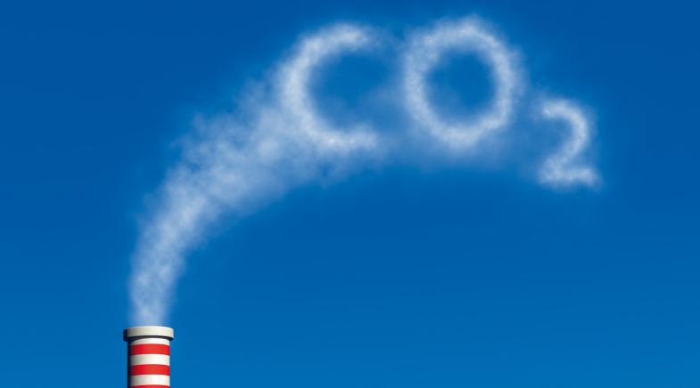 Ein Schlot bläst weißen Rauch aus, der den Begriff CO2 formt.