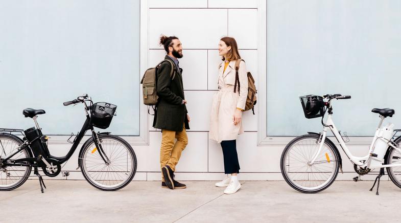Ein junges Paar steht sich gegenüber, hinter ihnen stehen ihre E-Bikes.