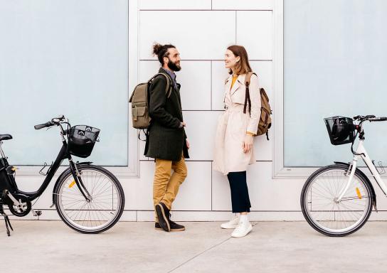 Ein junges Paar steht sich gegenüber, hinter ihnen stehen ihre E-Bikes.