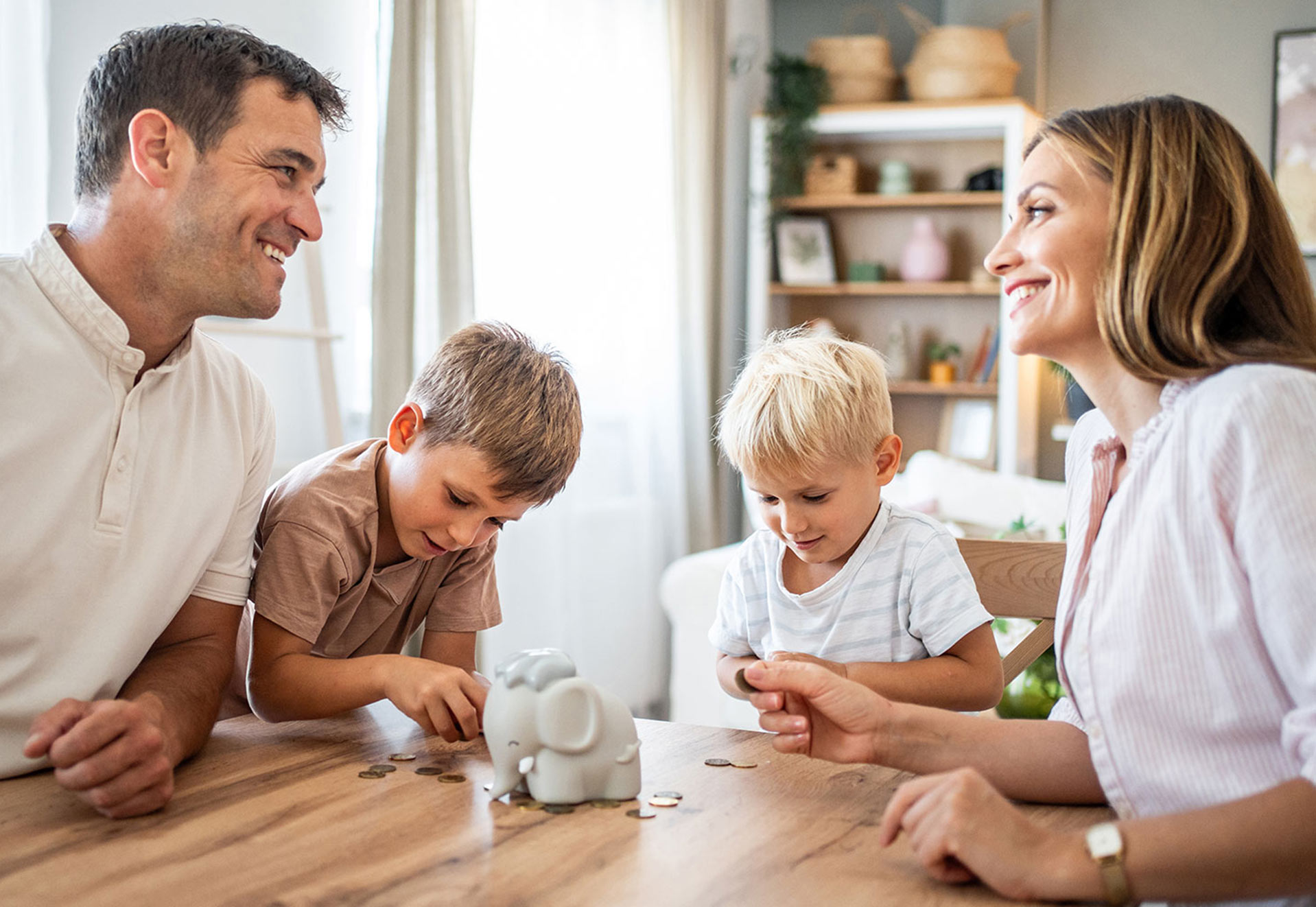 Familie sitzt am Tisch und sortiert Münzen in eine Sparbüchse.
