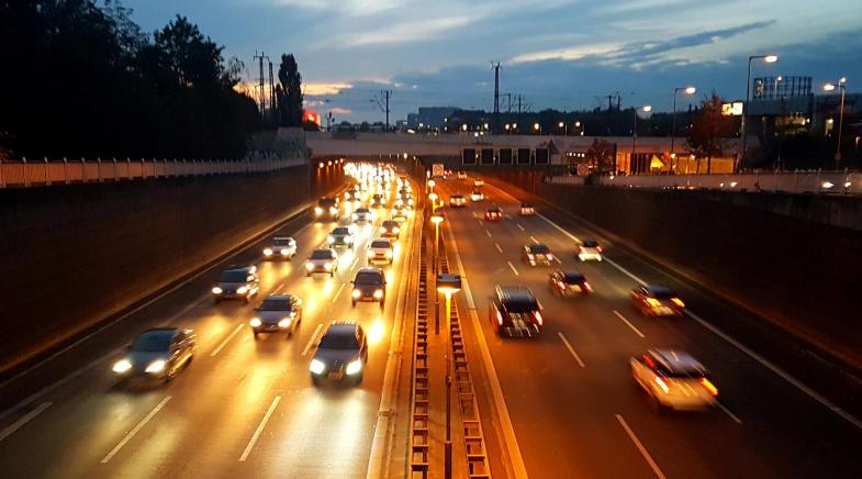 Eine dreispurige Autobahn mit fließendem Verkehr bei Nacht.