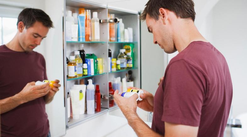 Ein Mann überprüft seine Hausapotheke in einem Badezimmerschrank.