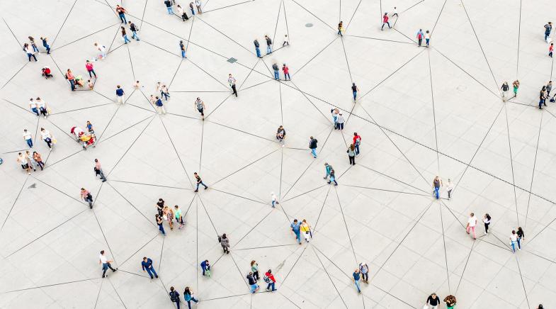 Viele verteile Menschen auf einem Platz mit Netzmuster auf dem Boden.