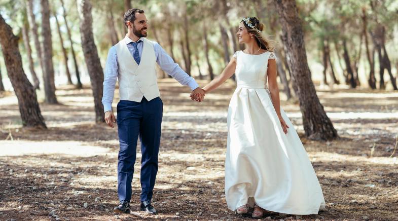 Hochzeitspaar geht Hand in Hand im Wald spazieren.