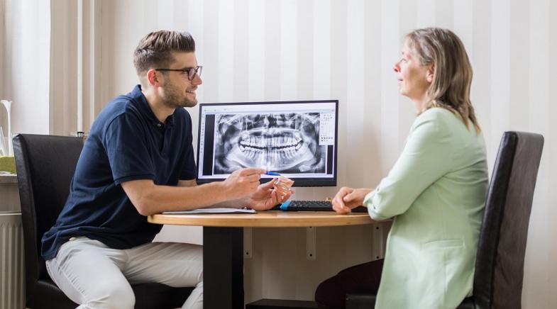 Ein Arzt berät am Schreibtisch eine Patientin.