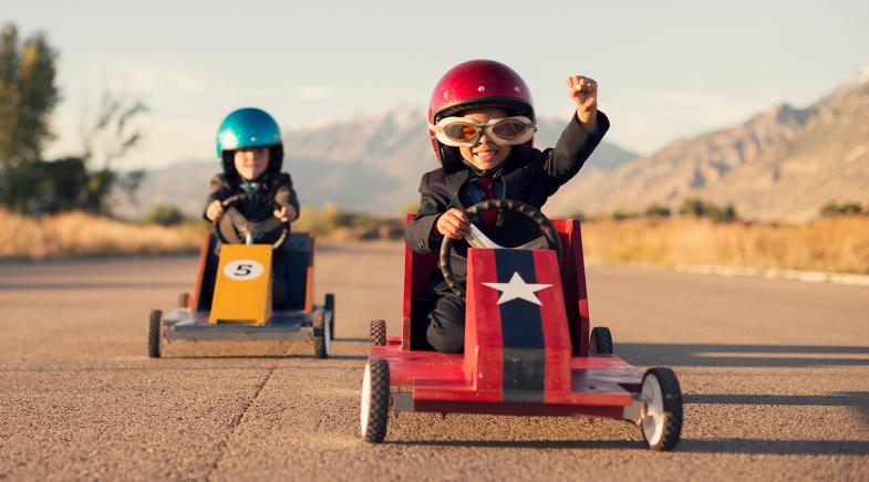 Zwei Kinder fahren ein Seifenkistenrennen.