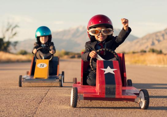 Zwei Kinder fahren ein Seifenkistenrennen.