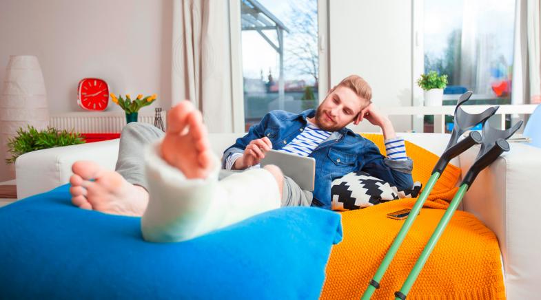 Junger Mann mit Gips auf dem Sofa