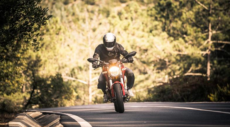 Ein Motorradfahrer fährt auf einer bewaldeten Landstraße.