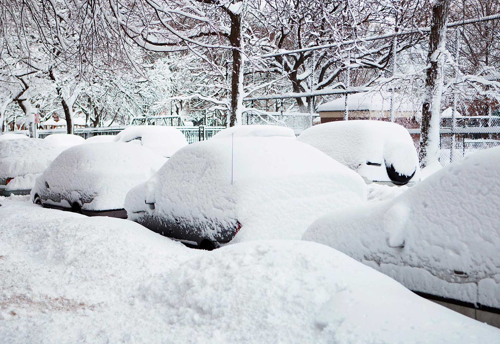 Völlig eingeschneite Autos parkend am Straßenrand im Winter.