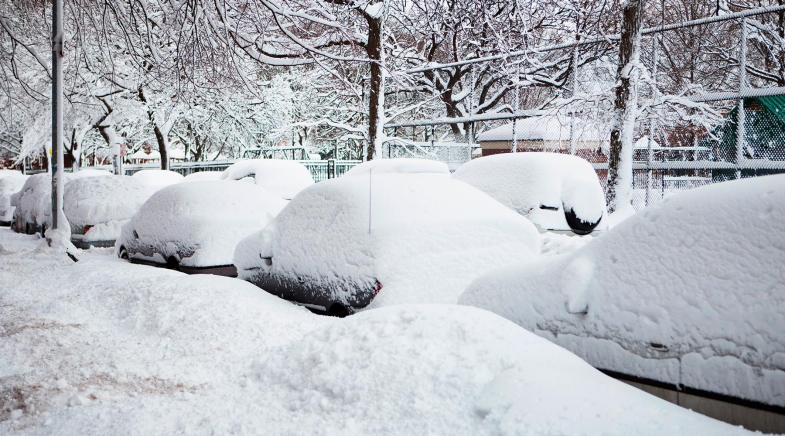 Völlig eingeschneite Autos parkend am Straßenrand im Winter.