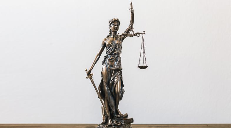 Kleine Statue der Justitia auf einem Schreibtisch.