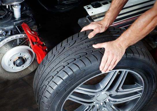 Großansicht einer Hand an einem Autoreifen beim Radwechsel