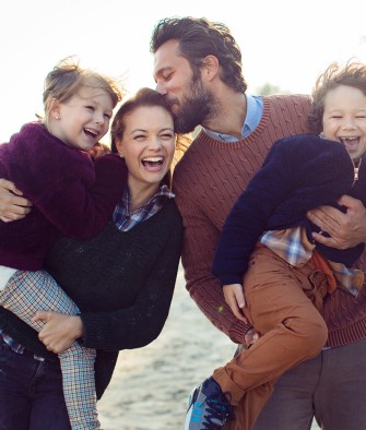 Junge Familie tollt am Strand herum.