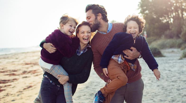 Junge Familie tollt am Strand herum.