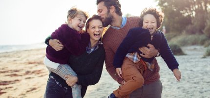 Junge Familie tollt am Strand herum.