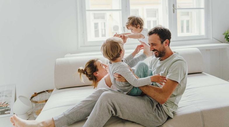 Familie mit zwei Kindern spielt auf einem Sofa