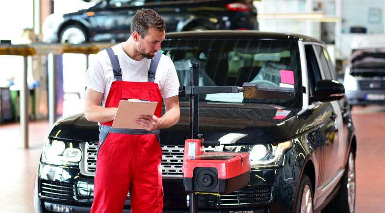 Mitarbeiter einer Autowerkstatt kontrolliert das Auto