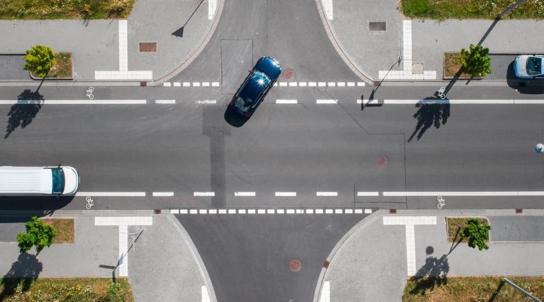 Kreuzung von oben: Ein Auto biegt links ab.