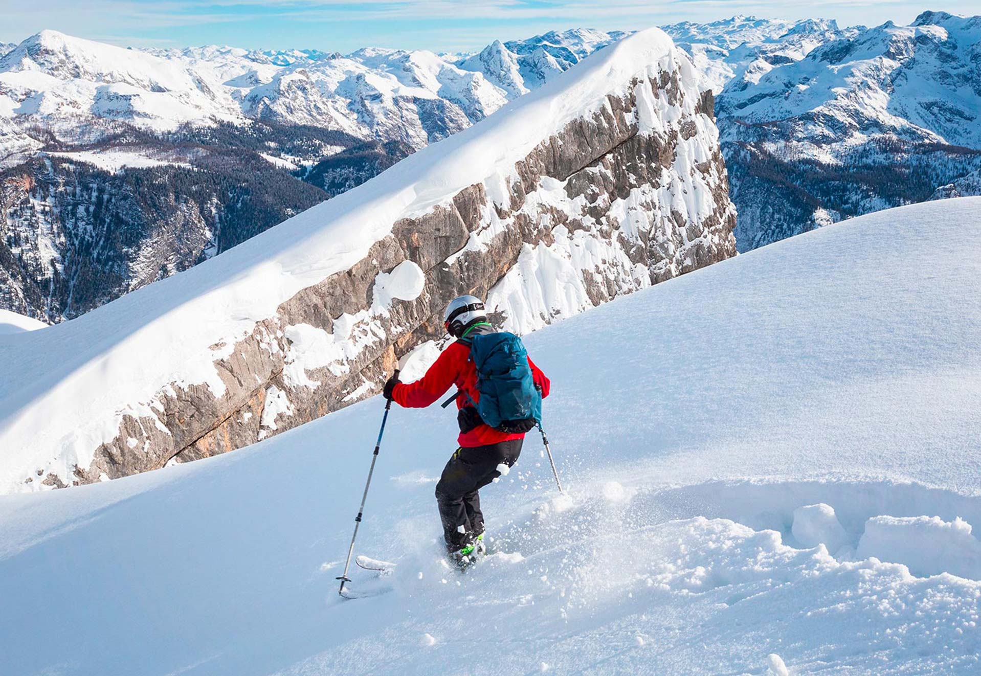 Ein Skifahrer fährt durch Tiefschnee bergab.