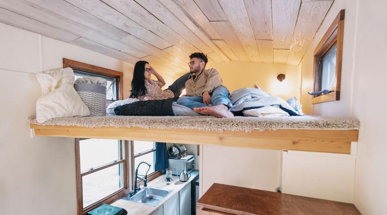 Ein Pärchen liegt im Bett eines Tiny House.