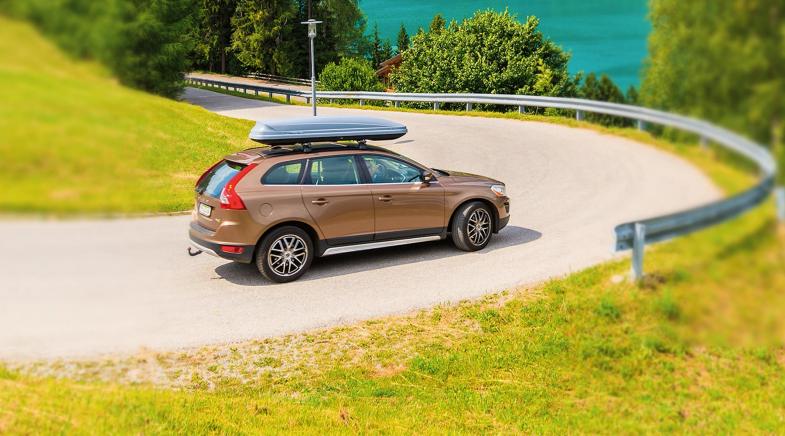 SUV mit Dachbox fährt Serpentinen herunter.