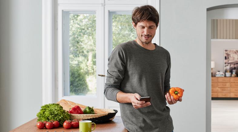 Mann in der Küche mit Paprika in der Hand