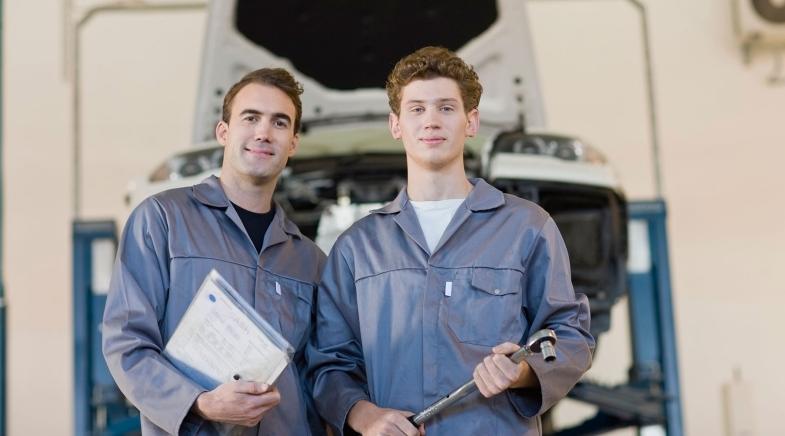 Zwei Automechaniker vor einer Hebebühne.