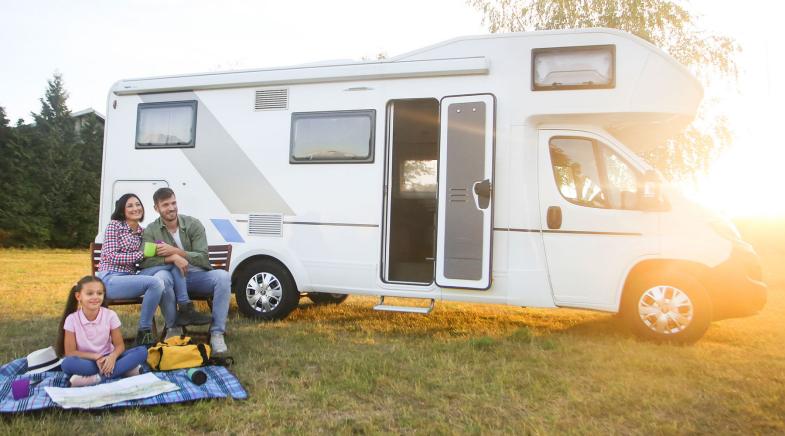 Familie sitzt vor ihrem Wohnmobil