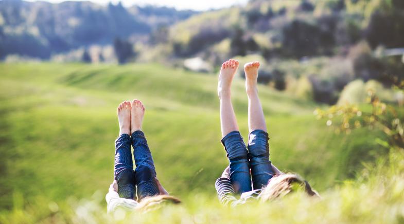 Zwei Kinder liegen auf einer Wiese.