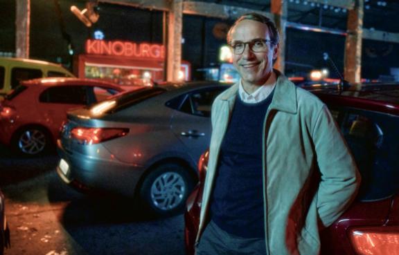 Herr Möller steht an einer Straße vor einem Kino