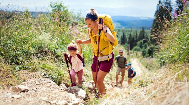 Familie wandert mit ihren zwei kleinen Kindern einen steilen Bergpfad hinauf