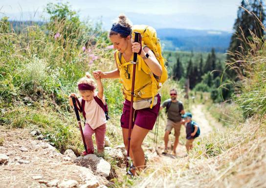 Familie wandert mit ihren zwei kleinen Kindern einen steilen Bergpfad hinauf