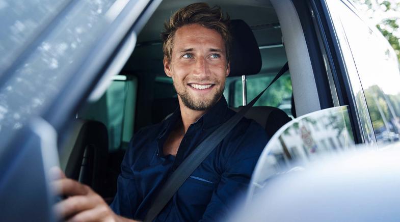 Mann sitzt im Auto und schaut aus dem geöffneten Seitenfenster.
