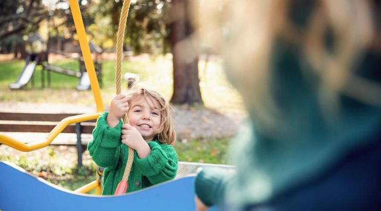 Ein Kind hält sich auf einem Spielplatz an einem Kletterseil fest.