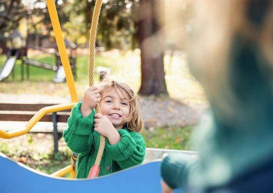 Ein Kind hält sich auf einem Spielplatz an einem Kletterseil fest.