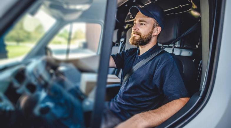 Handwerker sitzt entspannt in seinem Fahrzeug.