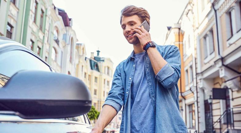 Mann steigt in sein Auto und telefoniert.