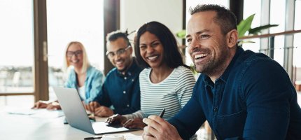 Diverse office colleagues laughing together during a meeting