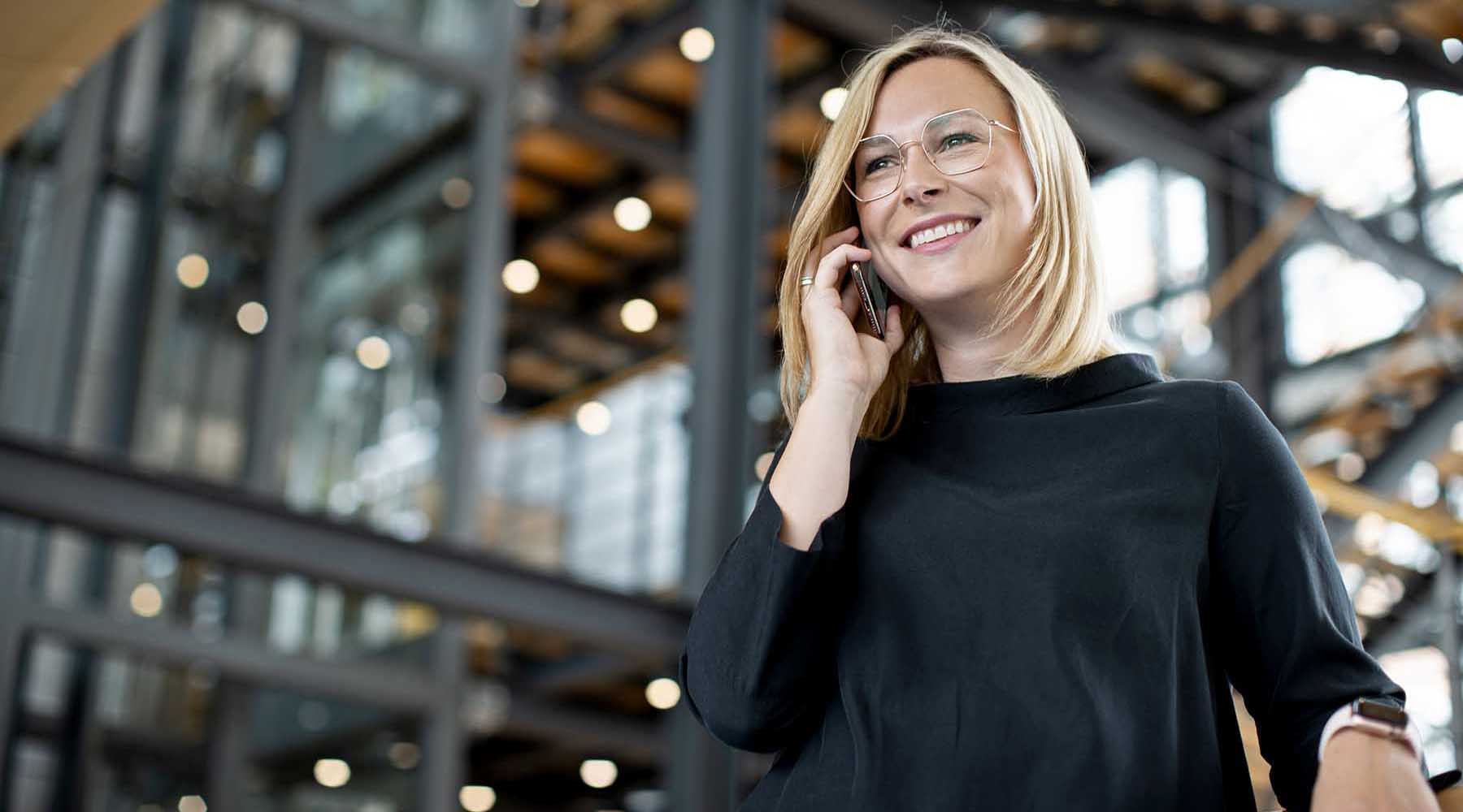 Frau telefoniert im Gebäude der HUK-COBURG mit dem Handy.